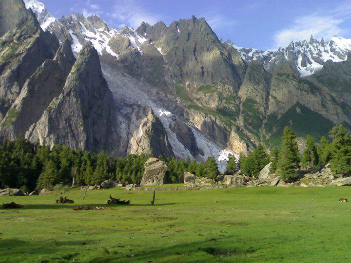 Green meadow in Haramosh Valley beneath snow-covered mountains